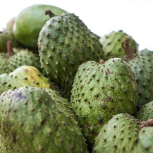 A pile of ripe soursop fruits displaying their distinctive green spiky texture, captured in detail.