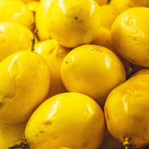 Vibrant yellow passion fruits stacked together, highlighting their freshness and texture.