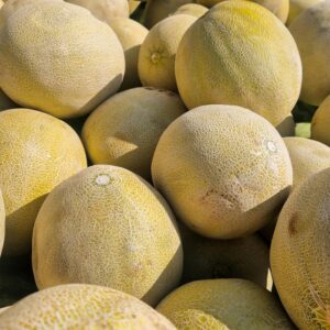 A pile of fresh yellow melons at an outdoor market in Guatemala City, showcasing local produce.