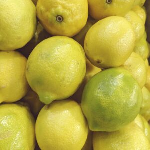 Close-up of fresh yellow lemons piled in a grocery store, showcasing vibrant colors.
