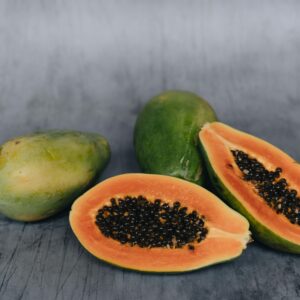 Sliced ripe papayas on a textured surface showcasing their vibrant orange flesh and black seeds.