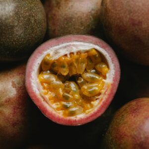 Closeup of half of fresh ripe passion fruit with yellow juicy flesh on heap of passion fruit