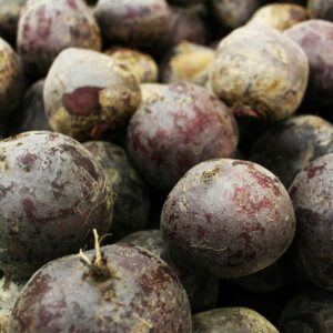 A pile of fresh, organic beetroots showcasing their natural texture and earthy colors.