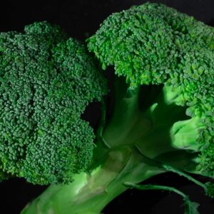 Vibrant close-up of fresh organic broccoli against a dark background.