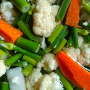 A vibrant close-up of fresh vegetables including carrots, cauliflower, and green onions.
