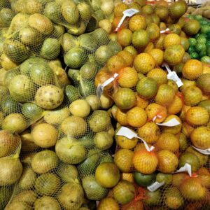Bountiful display of oranges and lemons in mesh bags at a grocery store.