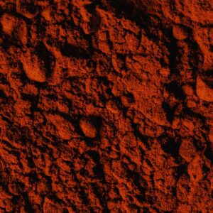 Detailed vertical shot showcasing the rich texture of paprika powder, emphasizing its vibrant red color.