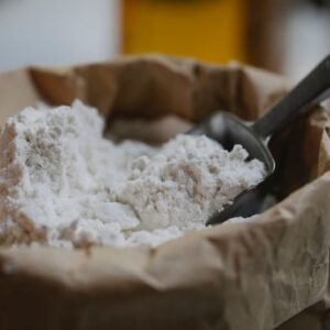 High angle of wheat flour with metal scoop prepared for pastry and cooking process