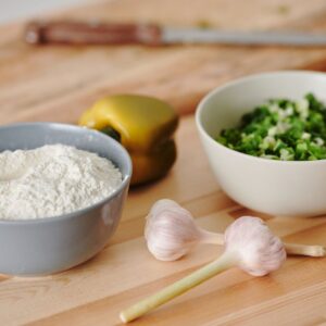 Fresh ingredients including flour, garlic, and scallions for cooking preparation.